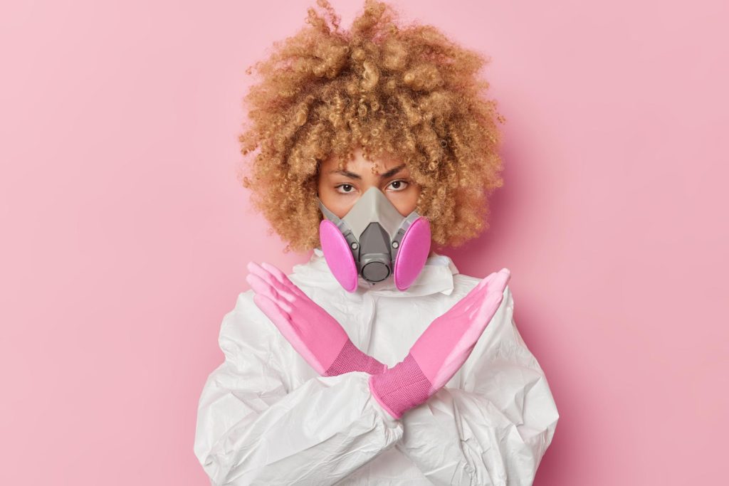 serious-young-woman-wears-chemical-protective-suit-respirator-makes-stop-gesture-taboo-sign-doesnt-allow-come-tries-prevent-danger-isolated-pink-background-biohazard-concept